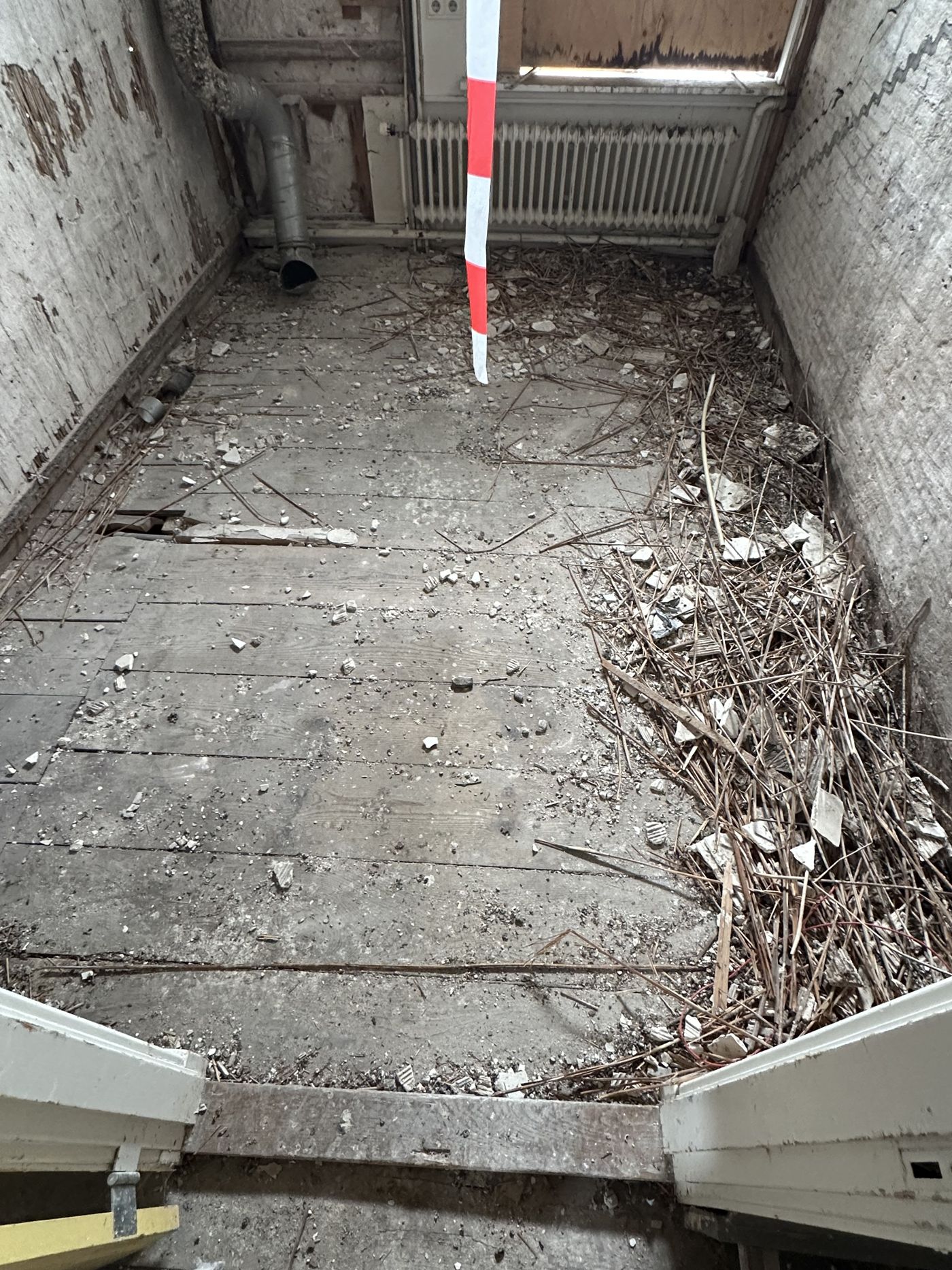Kamer vol puin en sloopresten op de vloer, vóór het bezemschoon maken