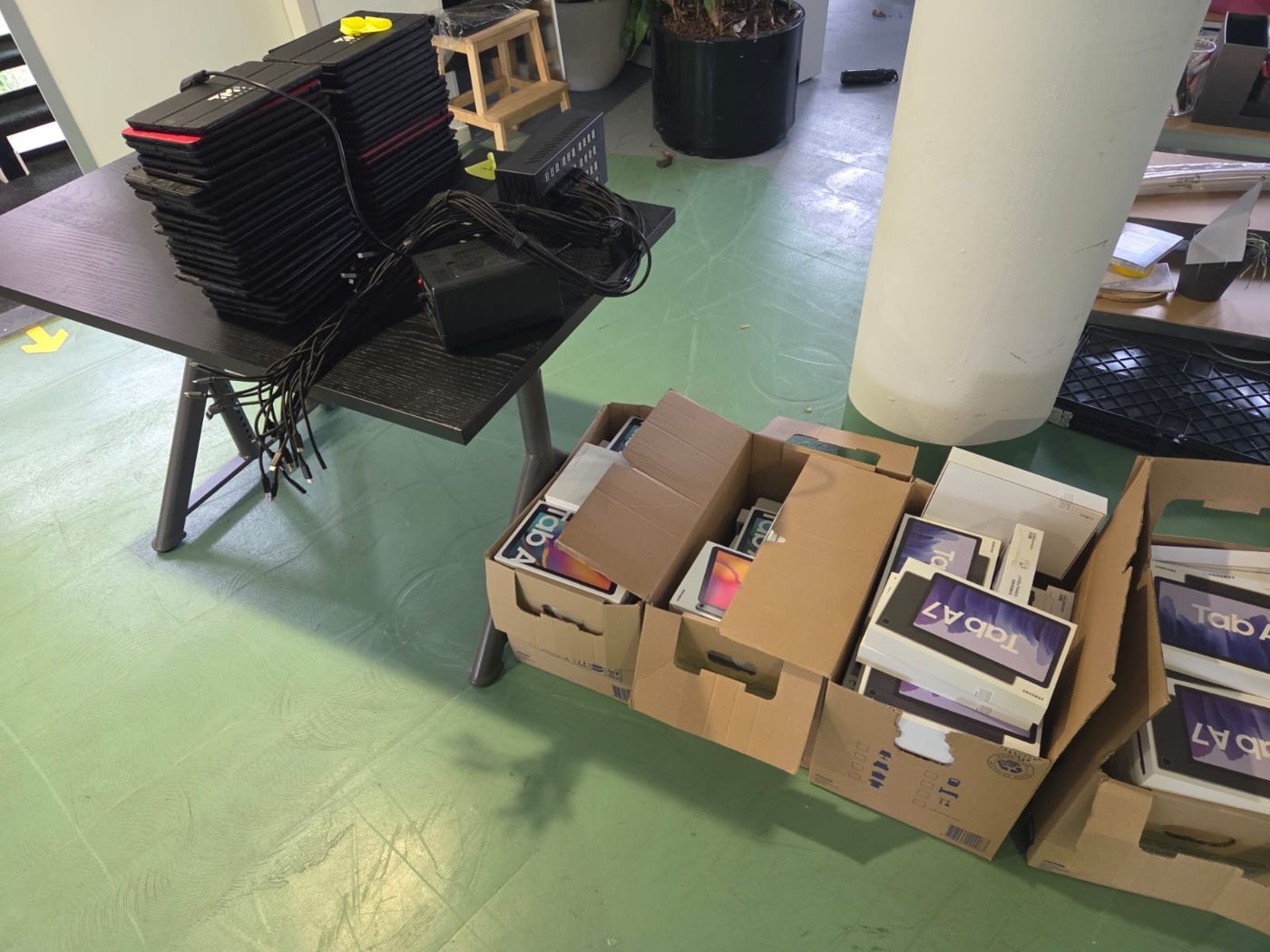 Tafel met laptops en dozen elektronica die bij de ontruiming zijn overgenomen
