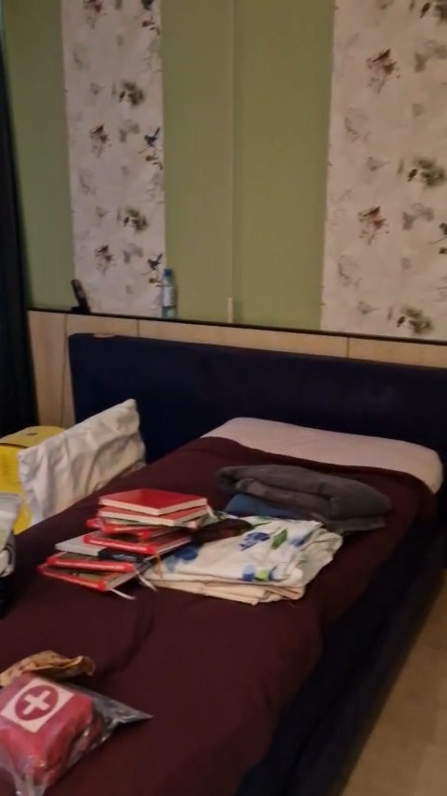 Slaapkamer met bed, boeken en spullen vóór de ontruiming