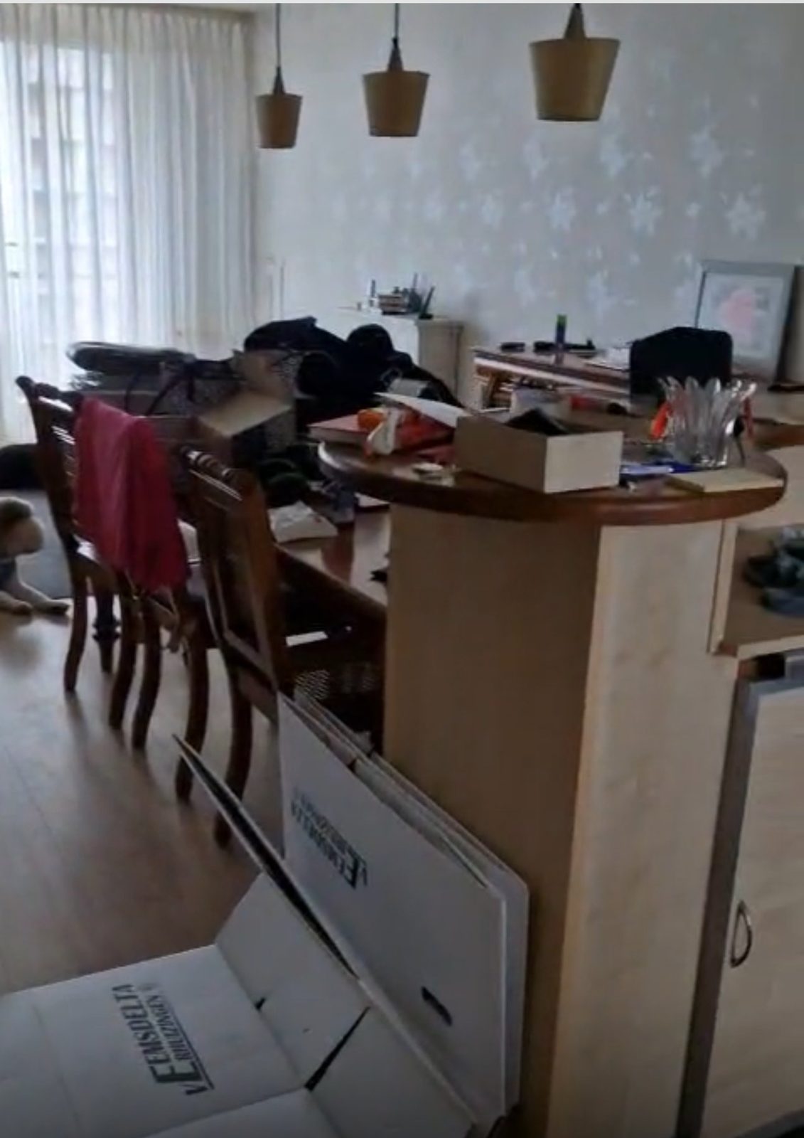 Woonkamer met volle eettafel, dozen en spullen vóór de woningontruiming in Purmerend